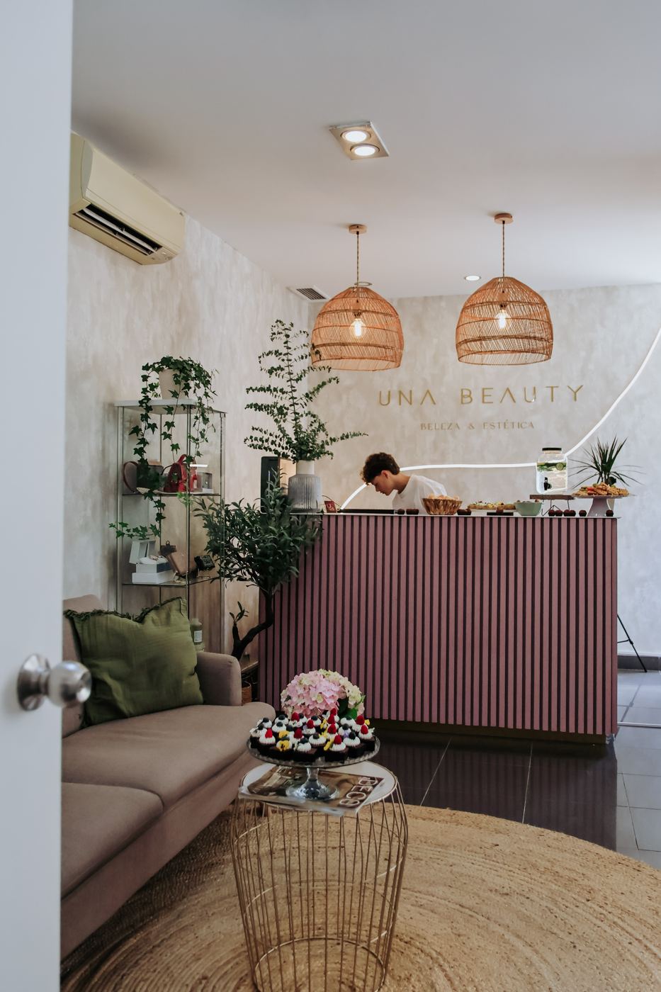 Interior do salão Una Beauty com balcão em ripado, plantas e luz natural