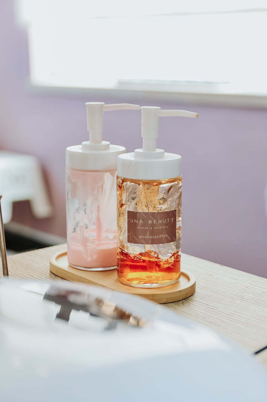 Produtos da marca Una Beauty em frascos sobre suporte de madeira no salão