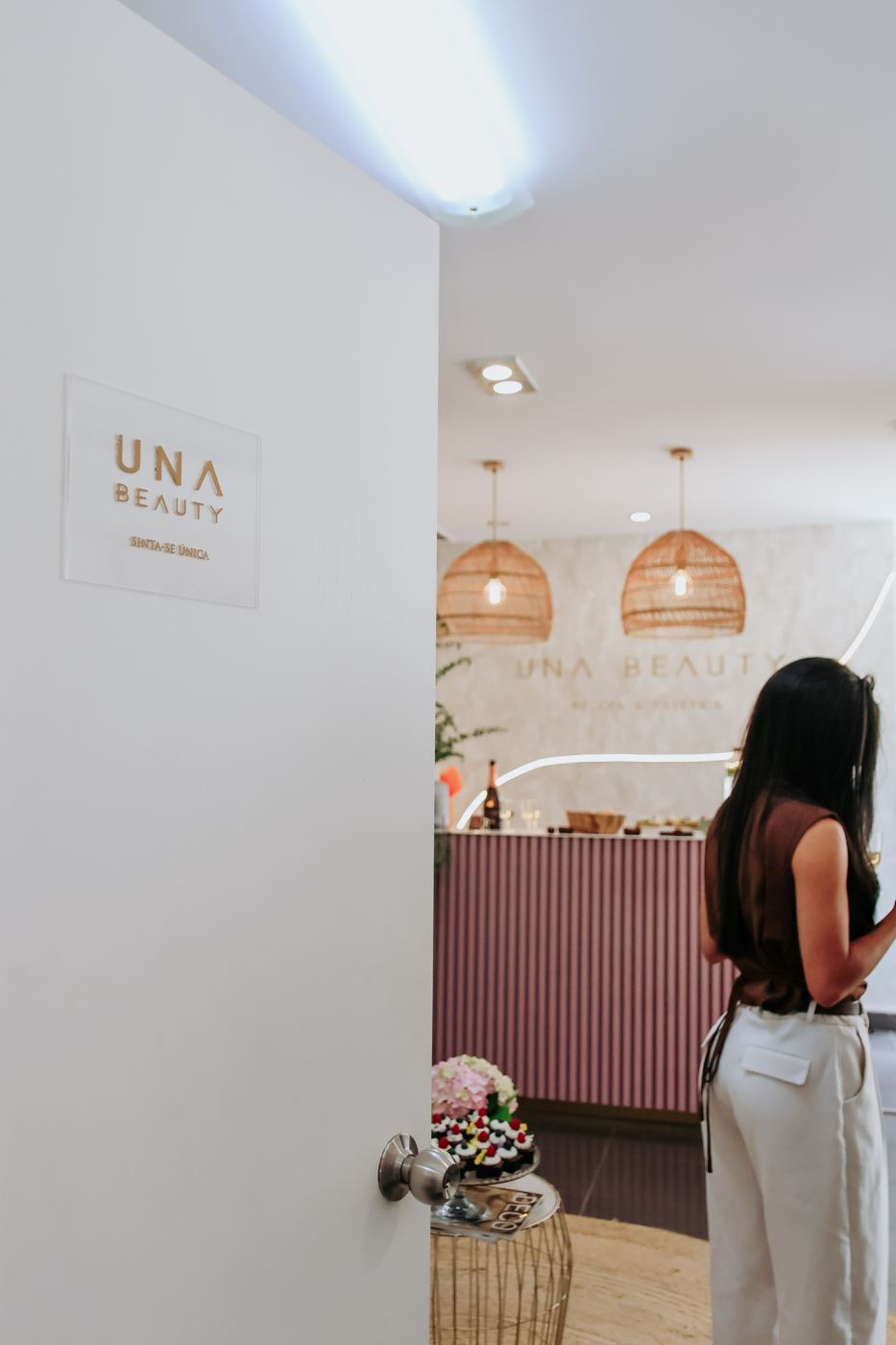 Entrada do salão Una Beauty com placa Sinta-se Única e vista para a recepção